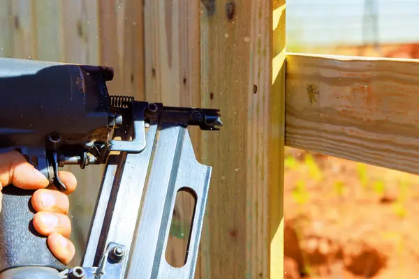 stock image Using an air pneumatic gun worker nails wooden plank fence during work