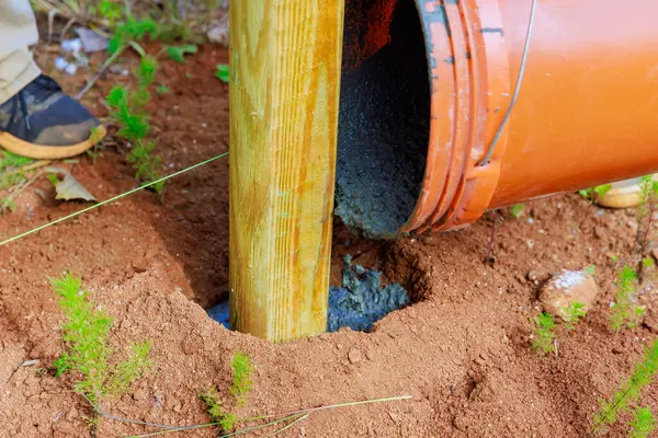 stock image Concrete pouring of newly installed timber fencing wooden fence posts