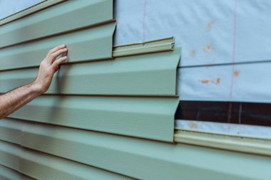 Contractor installing vinyl siding plastic panels on facade wall of new home clipart