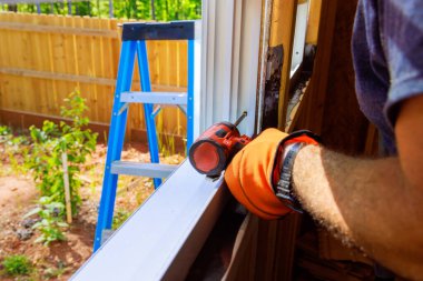 İnşaat işçisi, yeni eve tornavida kullanarak pencere kuruyor