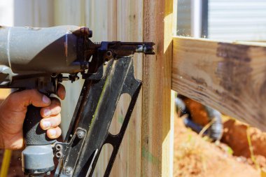 İşçiler iş sırasında hava basınçlı silah kullanarak çitleri çiviliyor.