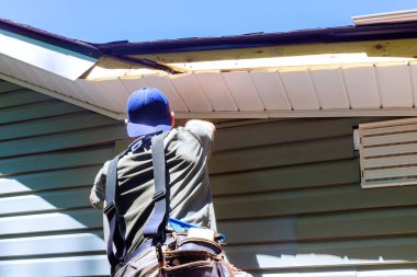 İnşaat sürecinde, bir çalışan yeni evin duvar cephesine plastik kaplama panelleri yerleştirir