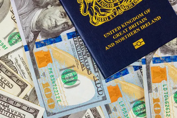 stock image A new biometric British passport with US currency dollars notes is symbolizing transatlantic relationship to travelling citizen United Kingdom of Great Britain