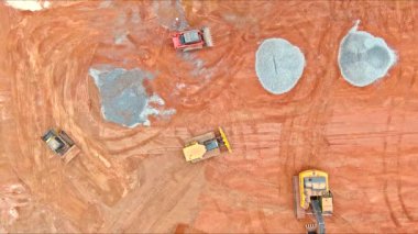 İnşaat alanının detaylı hava görüntüleri, traktörler, buldozerler, araziyi şekillendirmek için hareket eden işçiler.