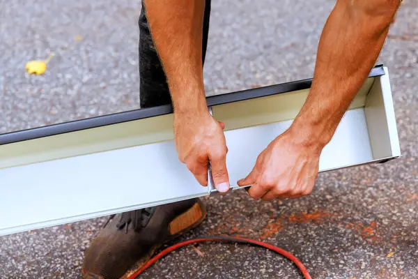 stock image Worker installing hidden gutter hangers with a pre inserted screw heavy duty rain gutter brackets fastener to new gutters before attachment on roofing