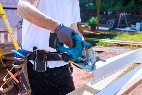 stock image Worker cuts plastic vinyl siding to size before installing it with circular handsaw