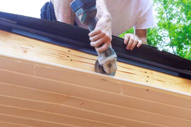 Çalışan, yeni ikamet yerinin ön cephesindeki plastik panelleri gerekli boyuta getirmek için kesiyor.