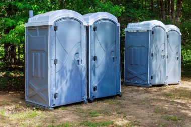 Long row portable bio of chemical toilets cabins in park center at city clipart