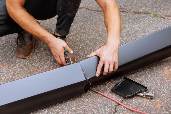 stock image When aluminum rain gutters have been bent on machine tool, worker cuts them to required size with shears