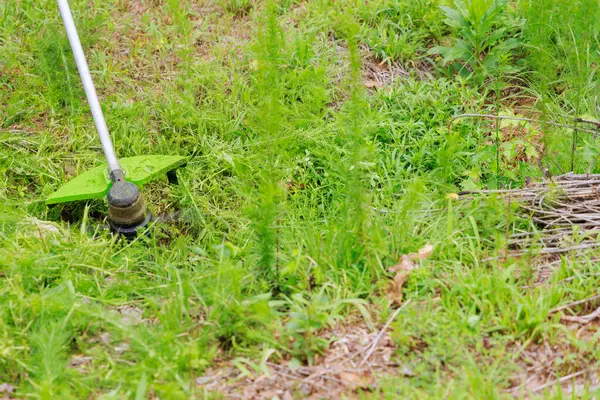 stock image Worker mows green grass on lawn with hand trimmer is lawn care weed garden work