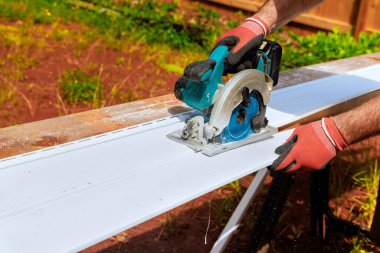 Dairesel el testeresi ile çalışan işçiler, yerleştirilmeden önce plastik kaplamaları boyutlarına göre kesiyorlar