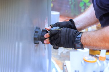 Bakım şirketinin bir çalışanı havuz klorlama sistemi, su filtreleme sistemi kuruyor.