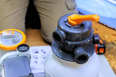 Yüzme havuzu bakım işçisi kum filtresi sistem tankını ve havuz temizleme ekipmanlarını kurar.