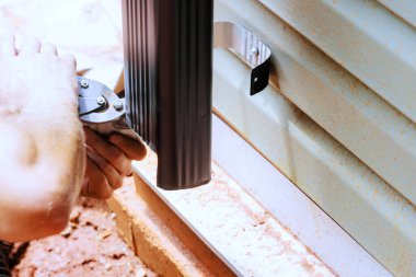 Metal makasla alüminyum yağmur oluğu kesen işçiler.