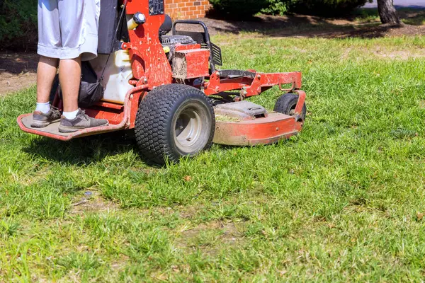 stock image Municipal employee mows grass in park using lawn mower tractor at landscaping works