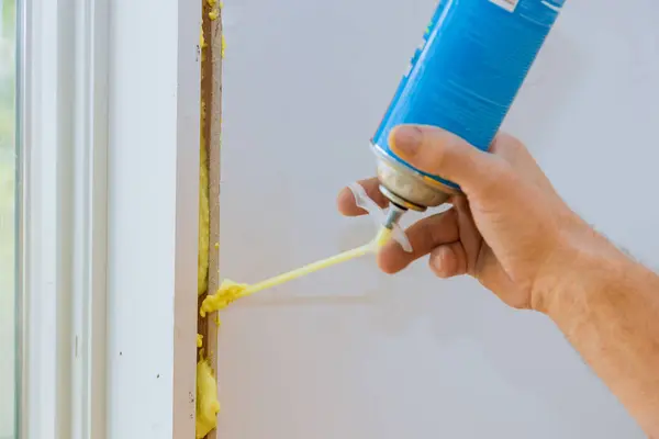 stock image Construction foam is blown into gap between window wall by worker