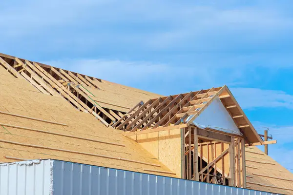 stock image Assembling roof of new house under construction using plywood on wooden trusses