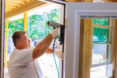 Pnömatik çivi tabancası kullanımı marangoz tarafından ön kapı yeni ev montajı sırasında gösterilir