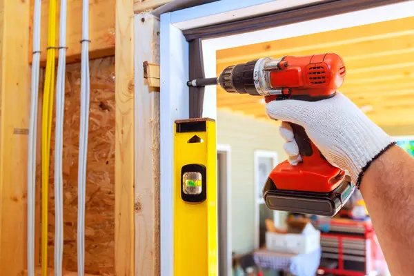 stock image Carpenter uses screwdriver to install front door of new home