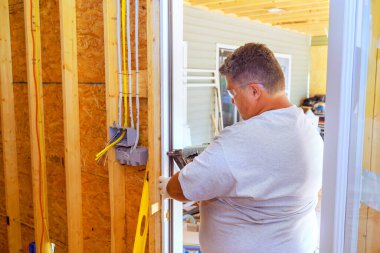 Pnömatik çivi tabancası kullanan marangoz, yeni evine ön kapıyı takıyor.