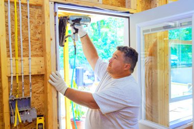 Carpenter yeni ev için yeni ön kapı monte etmek için pnömatik çivi tabancası kullanıyor.