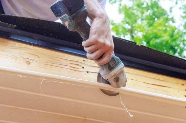 Cutting off established vinyl soffit panels facade ceiling of new house to a given size clipart