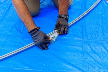 Yerüstü havuzu için metal çerçeve montajı sırasında, işçiler çalışıyor