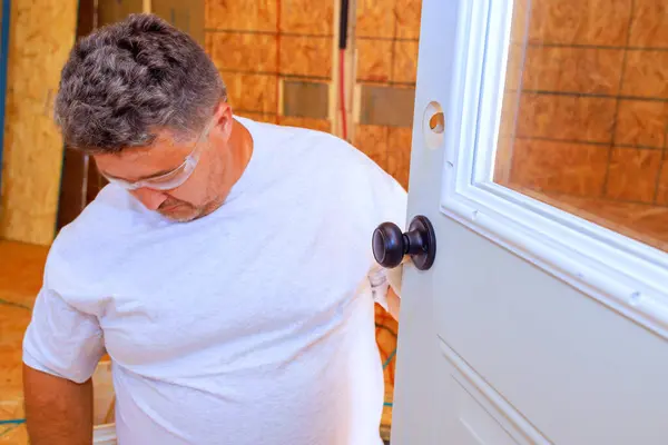 stock image Lock doorknob installed by professional locksmith using screwdriver on an entrance door to house