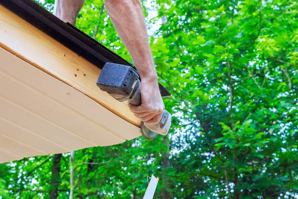 stock image Cutting off established vinyl soffit plastic panels to specified size on facade ceiling of new house by an employee