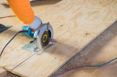 İşçi, dairesel testere kullanarak ahşap kontrplak keser.