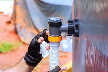 Bir çevre bakım şirketinin çalışanı, yüzme havuzu iskeleti için klor sistemi olan su filtreleme sistemi kurar.