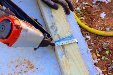 Yeni evin çerçevelenmesi sırasında, hava basınçlı çekiçler ahşap kirişleri betona çakmak için kullanılır.