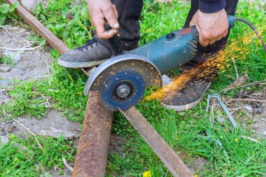 İşçi metal çerçeveleri kesmek için el testeresi kullanıyor.