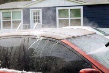 Arabayı dışarıda yıkamak için basınç altında su jeti kullanmak.