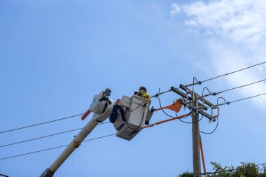 Yalıtımlı ekipman kullanan elektrik mühendisi elektrik hattındaki hizmeti sürdürmek için direkte çalışıyor.