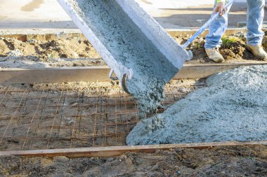 Beton karıştırıcı kamyon tarafından yeni kaldırım için güçlendirilmiş demirlere taze beton dökülüyor.