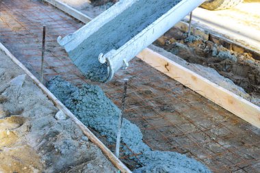 Beton karıştırıcı kamyon kaldırım hazırlığı için güçlendirilmiş parmaklıklara taze beton döküyor.