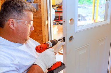 Profesyonel çilingir tornavida kullanarak giriş kapısına kilit takar.