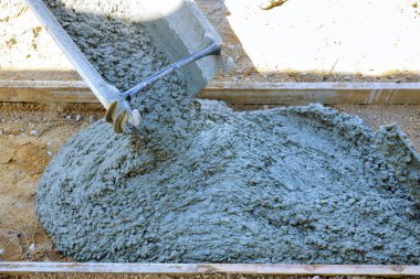 Beton karıştırıcı kamyon yeni kaldırım inşaatı için güçlendirilmiş parmaklıkların üzerine taze beton döküyor.