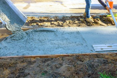 Beton kamyonlu yeni kaldırım inşaatı için güçlendirilmiş parmaklıkların üzerine taze beton dökülüyor.