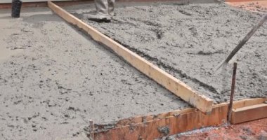 İnşaat alanında beton döşeyen bir inşaat işçisi.