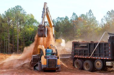 İnşaat alanındaki kazıcıyı kullanarak araziyi çöp kamyonuna yüklüyorum.
