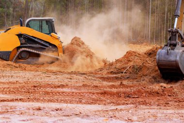 Toprak işlerinde, küçük toprak hareket eden traktör inşaat sırasında zemini düzleştiriyor.