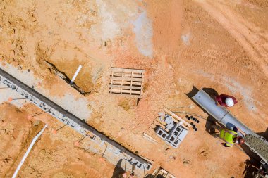 İnşaat işlerinde kullanılan beton karıştırıcı kamyonla bölgedeki temel duvarlara kırmızımsı toprak dökülüyor..