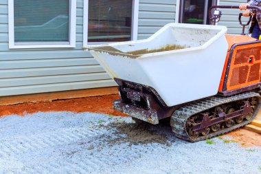 Kompakt, izi sürülen atık araçları ıslak beton döşeme sahasında, evin dışındaki temele hazırlanıyor.