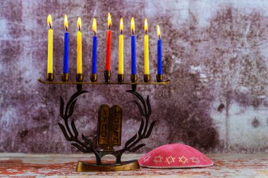 Menorah with nine lit candles, kippah resting on a wooden table of Jewish tradition holiday Hanukkah is symbolizing light clipart