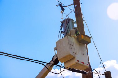 Teknisyen uzun direğe bağlı servis elektrikli ekipmanlarını yerleştirmek için kova kaldırmadan güvenli bir şekilde çalışır..