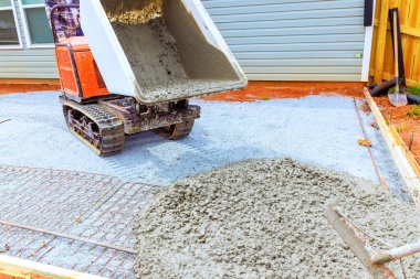 Ağır makineler, kenar mahallelerdeki yeni teras işçilerinin yol gösterici olarak kullandıkları kompakt dökümcüleri kullanarak hazırlanan alana taze beton dağıtıyor.