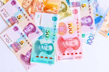 Çeşitli Çin Yuan banknotları beyaz yüzeye yayılmış, farklı değerler, özlü para çeşitliliği sergiliyor..