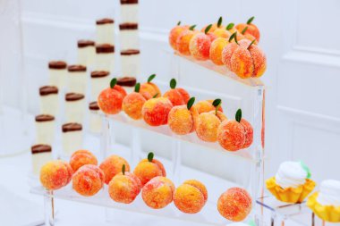 Lezzetli tatlı şeftali şekilli şekerler çok katmanlı tezgahlarda çok güzel bir şekilde düzenlenmiştir. Kutlama etkinliğinde.